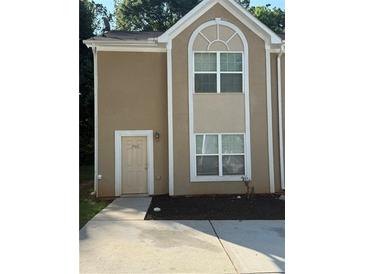 Inviting townhome featuring a neutral stucco facade, complemented by crisp white trim and a well-manicured landscape at 2960 Fields Dr, Lithonia, GA 30038