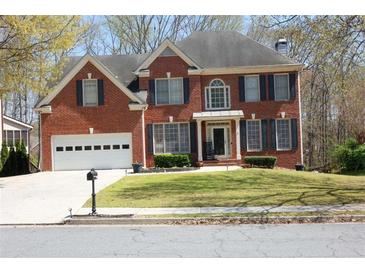 Charming two-story red brick home with well-maintained lawn and two-car garage at 3220 Warren Creek Dr, Powder Springs, GA 30127