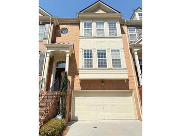 Inviting brick townhome featuring a two-car garage and stylish architectural details at 4621 Wehunt Commons Se Dr # 7, Smyrna, GA 30082