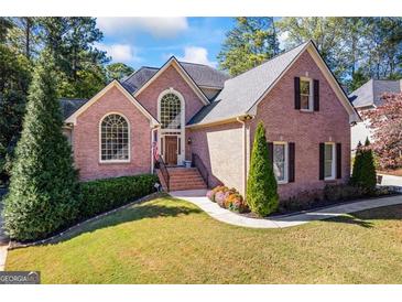 Charming brick home showcasing manicured lawn and attractive landscaping, with traditional architectural details at 560 Hunt River Way, Suwanee, GA 30024