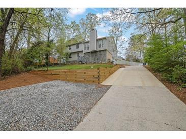 View of the house with a long driveway, retaining wall and landscaping at 2775 Whippoorwill Cir, Duluth, GA 30097