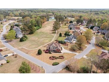 Beautiful aerial view of a red brick home with manicured lawn in a lovely neighborhood with a pond in the distance at 179 Country Club Dr, Hiram, GA 30141