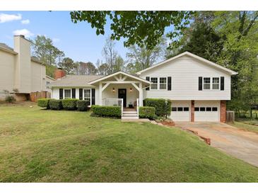 Charming two-story home with a well-manicured lawn, two car garage, and a welcoming front porch at 1068 Gwens Sw Trl, Lilburn, GA 30047
