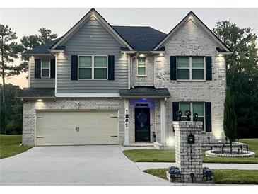 Charming two-story home with brick and gray siding, a manicured lawn, and a two-car garage at 1861 Poplar Falls Ave, Lithonia, GA 30058