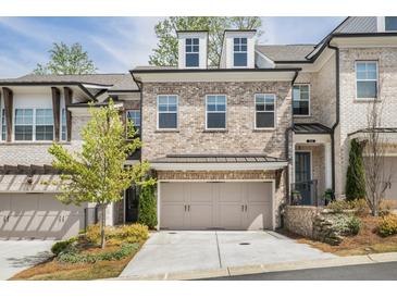 Charming two-story brick townhouse with a two-car garage and well-manicured landscaping at 306 Atley Pl, Alpharetta, GA 30009