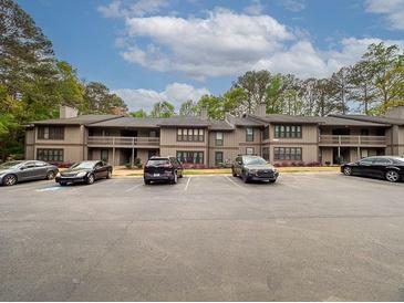 Multi-Gathering exterior featuring balconies, parking spaces, and a wooded perimeter on a sunny day at 408 Smokerise Se Cir, Marietta, GA 30067