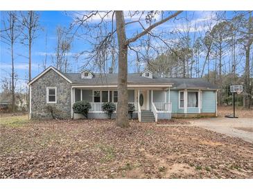 Charming single-story home with stone accents, a welcoming front porch, and a basketball hoop in the driveway at 265 Winding Stream Trl, Hampton, GA 30228
