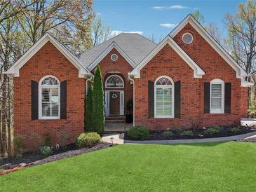 Charming brick home with arched windows, manicured lawn, and mature landscaping at 6060 Masters Club Dr, Suwanee, GA 30024