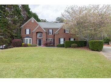 Charming two-story brick home with a well-manicured lawn and blooming tree at 2555 Stonevalley Ln, Cumming, GA 30041