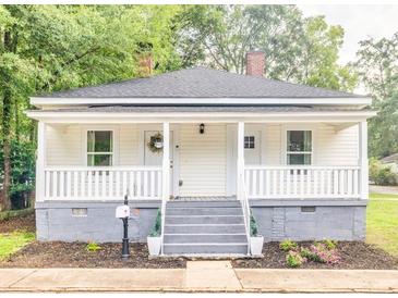 Charming single-story home with a cozy front porch, fresh landscaping, and a welcoming entrance at 13 E Palmetto St, Porterdale, GA 30014