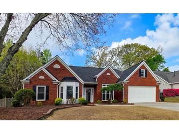Charming one-story brick home featuring a well-manicured lawn, dormer windows, and attached two car garage at 2004 Westover Nw Ln, Kennesaw, GA 30152