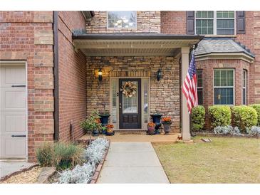 Charming brick home featuring a stone entryway and a beautifully decorated front door with seasonal accents and inviting curb appeal at 4560 Evandale Way, Cumming, GA 30040