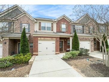 Charming brick townhome featuring a one-car garage and well-maintained landscaping at 7701 Haynes Park Pl, Lithonia, GA 30038