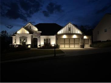 Beautifully lit home exterior featuring a stone and brick facade, complemented by an attached three-car garage at 432 Horizon Trl, Canton, GA 30114