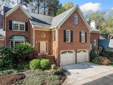 Charming two-story brick home with a well-manicured front yard and attached two-car garage, offering classic curb appeal at 51 Ivy Chase Ne, Atlanta, GA 30342