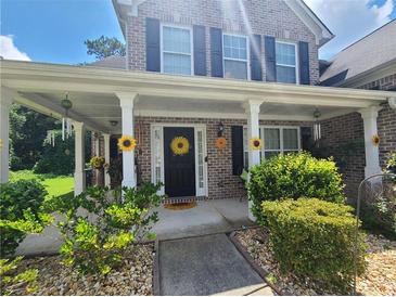 Charming brick home featuring a welcoming front porch adorned with sunflower decorations and lush landscaping at 828 Cooper Lakes Ct, Grayson, GA 30017