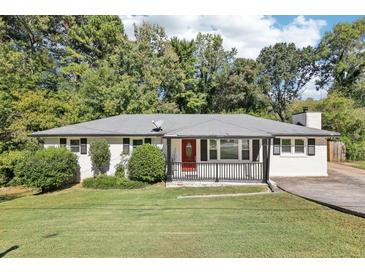 Charming one-story home featuring a landscaped front yard and a welcoming red front door at 100 Charlotte Sw Dr, Mableton, GA 30126