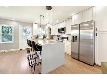 Bright kitchen features white cabinets, stainless steel appliances, and a quartz island with pendant lighting at 1751 Carter Cir, Atlanta, GA 30344