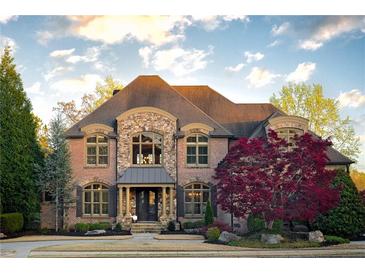 Elegant brick home featuring a stone facade, manicured lawn, and mature landscaping at 3053 Cambridge Hill Dr, Dacula, GA 30019