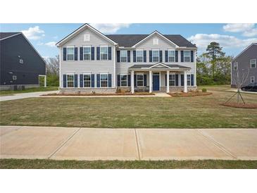 Charming two-story home with blue shutters, covered porch, and well-maintained lawn at 156 Marchmont Dr, Locust Grove, GA 30248