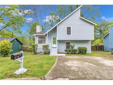 Charming two-story home featuring light blue siding, green front door, tidy landscaping, and a welcoming front yard at 1077 Mainstreet Valley Dr, Stone Mountain, GA 30088