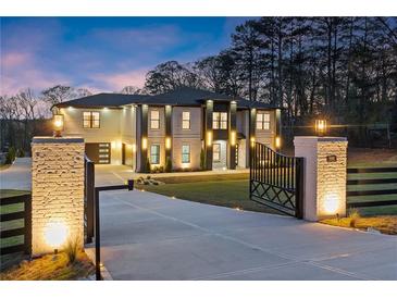 Stunning two-story home with a gated entrance and brick accents illuminated by stylish outdoor lighting at 1688 Mineral Springs Rd, Hoschton, GA 30548