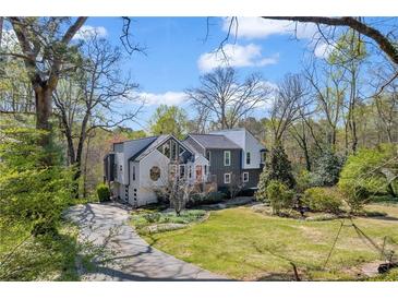 Charming two-story home with an attractive front yard and lovely landscaping on a partly cloudy day at 10845 Shallowford Rd, Roswell, GA 30075