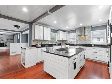 Bright kitchen featuring white cabinets, a gray backsplash, black countertops and stainless steel appliances at 1647 Grandeus Sw Ln, Stone Mountain, GA 30087