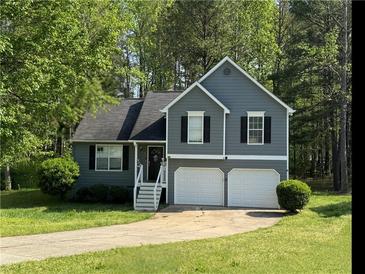 Charming two-story home featuring a two-car garage, gray siding, and a well-manicured front yard at 3304 Mooring Dr, Powder Springs, GA 30127