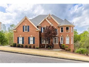 Elegant two-story brick home featuring a manicured lawn and a classic design with blue shutters and a turret at 4020 Balleycastle Ln, Duluth, GA 30097