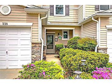 Charming townhome featuring a welcoming entrance with beautiful landscaping and a one-car garage at 338 Oak Leaf Pl, Acworth, GA 30102