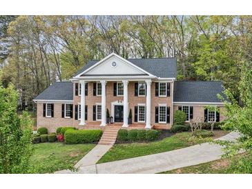 Stately brick home with white columns, black shutters, and mature landscaping provides classic curb appeal at 6124 Kings Mountain Ct, Stone Mountain, GA 30087