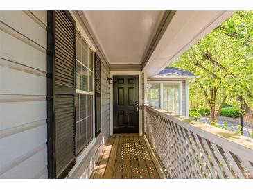 Charming front porch with wooden flooring, black door, and wooden lattice fencing at 104 Natchez Trce, Atlanta, GA 30350