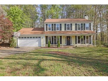 Charming two-story home with a welcoming front porch and well-maintained lawn in a wooded setting at 925 Crab Orchard Dr, Roswell, GA 30076