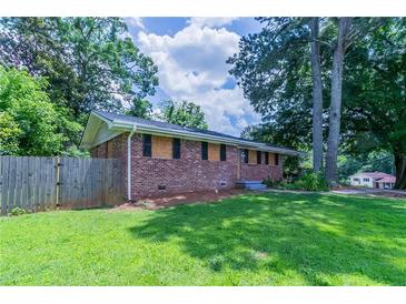 Charming brick home featuring a spacious lawn and mature trees creating a serene and private setting at 3932 Lindsey Dr, Decatur, GA 30035
