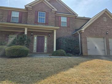 Charming two-story brick home featuring a two-car garage, covered entrance, and well-manicured landscaping at 1440 Gallup Dr, Stockbridge, GA 30281