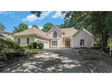 Charming home featuring a stone facade, arched entryway, and well-manicured landscaping, creating an inviting curb appeal at 370 Royal Birkdale Ct, Johns Creek, GA 30097