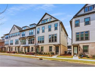 Row of craftsman townhomes featuring neutral colors, brick accents, and well-maintained landscaping under a blue sky at 3980 Allegretto Cir, Atlanta, GA 30339