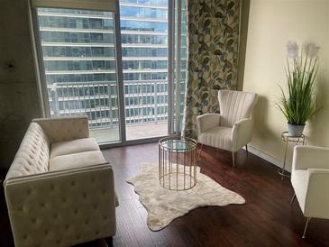 Bright living room featuring a plush sofa, chairs, and stunning city views from a private balcony at 855 Peachtree Ne St # 1912, Atlanta, GA 30308