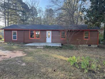 Charming single-story home featuring brown wood siding, a white front door, and orange window trim at 144 Flat Rock Rd, Oxford, GA 30054