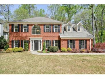 Charming two-story brick home with black shutters and a well-manicured front lawn surrounded by mature trees at 1010 Allenbrook Ln, Roswell, GA 30075