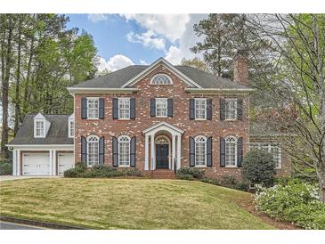 Elegant two-story brick home with symmetrical facade, black shutters, and a well-manicured front lawn at 4503 Payton Oaks Ne Pl, Atlanta, GA 30345