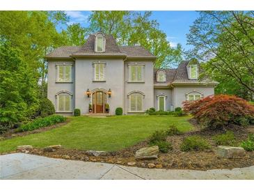 Stately two-story home with a manicured lawn, and lush landscaping at 302 Rolling Rock Se Rd, Marietta, GA 30067