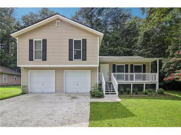 Charming two-story home with a two-car garage and a covered porch nestled among lush green trees at 3980 Carlton Cove Ct, Loganville, GA 30052