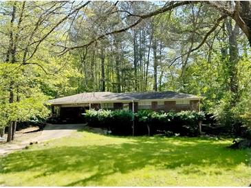 Charming one-story brick home featuring a covered carport and a lush, green lawn surrounded by mature trees at 2903 Vogue Dr, Douglasville, GA 30134