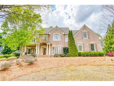 Stately brick home with manicured lawn and mature trees, featuring a covered porch and multiple windows at 2281 Bransley Pl, Duluth, GA 30097