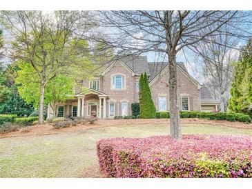 Charming two-story brick home featuring a manicured lawn with mature trees and blooming bushes at 2281 Bransley Pl, Duluth, GA 30097