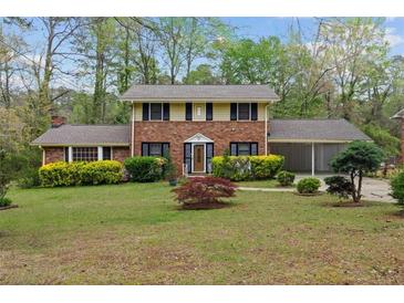 Charming two-story brick home featuring a well-manicured front yard, attached carport, and mature trees at 4606 Greensprings Rd, College Park, GA 30337