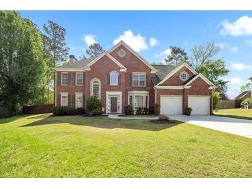 Beautiful two-story red brick home with a manicured lawn and three-car garage in a suburban setting at 5296 Camden Lake Nw Pkwy, Acworth, GA 30101