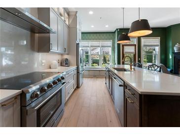 Gourmet kitchen features stainless steel appliances, custom cabinetry, and a large center island with bar seating at 2630 Milford Ln, Alpharetta, GA 30009